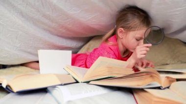 6-7 yaşlarında tatlı bir kız kitap okuyor. Evdeki küçük kız kırmızı elbisesiyle battaniyenin altında ön planda bir sürü kitabı olan. Kitaptaki bilgileri büyüteçle ara