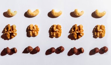 Gri arkaplanda izole edilmiş karışık fındık ve kurutulmuş meyve deseninden oluşan arkaplan düzeni.