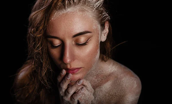 Fine art portrait. The woman\'s naked wet body is covered with a thin layer of flour. Creative body makeup with cracks and mud. Woman bodyart texture