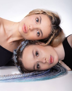 Güzellik konsepti. Beyaz arka planda kameraya birlikte neşeli pozlar veren iki beyaz kadın mükemmel cilt ve dudaklarla yüz yüze yatıyor. Yüz tedavisi.