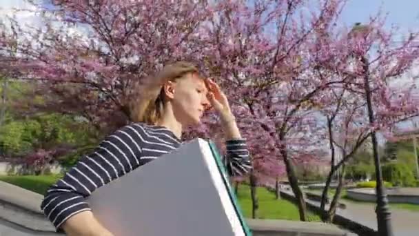 视频购物或递送的概念 一个戴着太阳镜 手里拿着一个空白纸盒的女人穿过了这个城市 — 图库视频影像