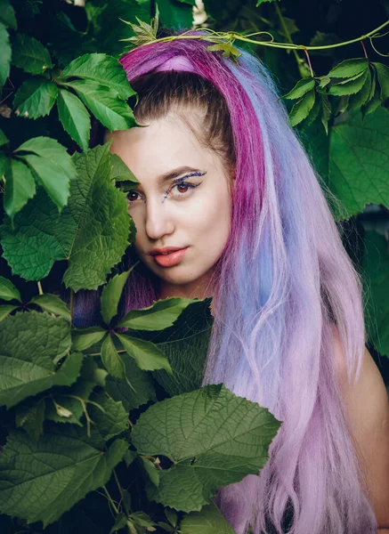 在公园的花木旁 绿叶上的年轻女子留着一头长长的紫色长发 在夕阳的余晖中度过了她的时光 — 图库照片