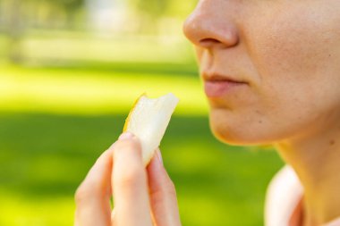 Toplum içinde yemek yerken ağzını kapat. Kadın şeftali ya da şeftali dilimleri tutuyor ve ısırıyor. Piknik konsepti