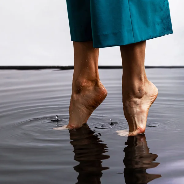 Amazing walking on water. Woman barefoot walking on the surface of the water floor. Close up legs of woman walking on floor flooded dark water