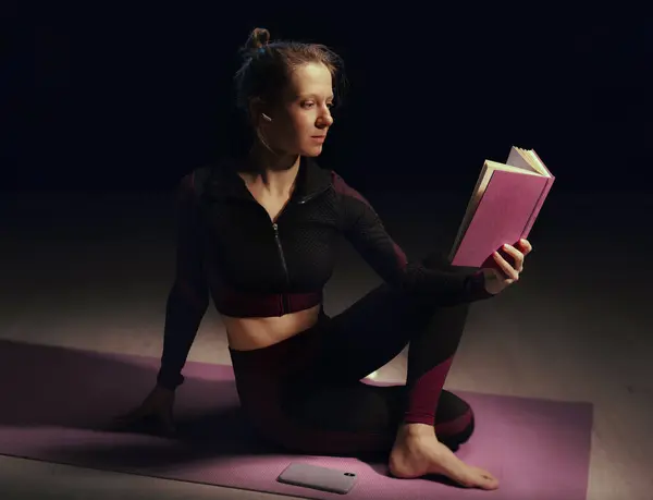 穿着运动服的女人晚上在家做瑜伽运动 时间管理概念 夜间锻炼瑜伽的女运动员 图库图片