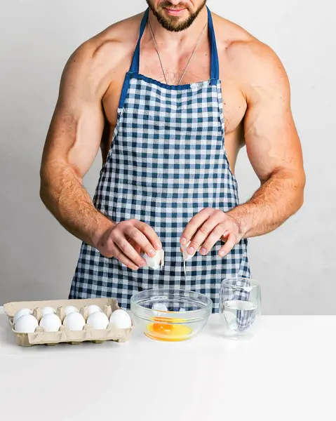 蛋白质食品概念 厨师健美师穿着防护围裙在厨房桌子上煮鸡蛋 肌肉男做饭 健康食品和节食 运动员的食品添加剂 每日蛋白质和卡路里 免版税图库图片