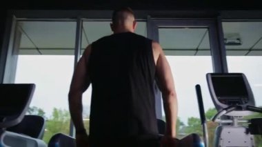 Koşu bandında egzersiz yapan bir adam, spor salonunda tek başına koşarken, mesajlaşmak için boş yeri olan bir adam..