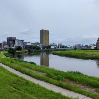 Kumamoto, Japonya - 18 Mayıs 2025. Arka planda Cityscape ile Shirakawa Nehri ve Köprüsü 'ne bak