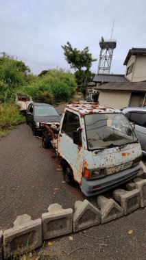 Kitakyushu, Japonya - 26 Mayıs 2025. Paslı Daihatsu Hijet ve diğer bakımsız arabalar.
