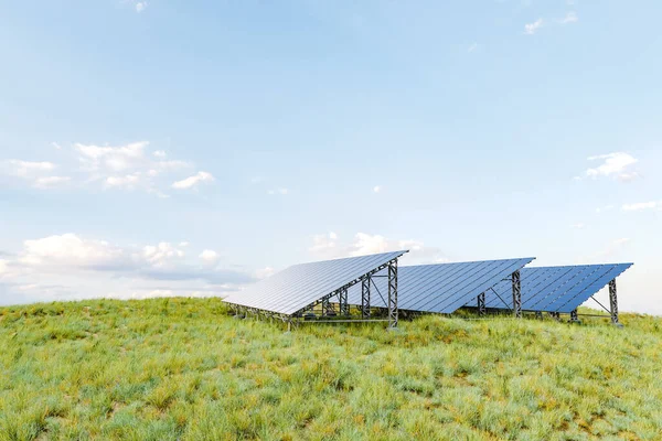 stock image 3D illustration of modern photovoltaic panels installed on green grass against cloudy blue sky on solar farm in meadow