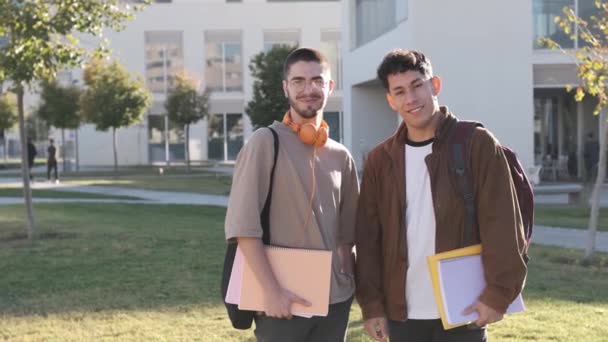 カメラで笑っている大学のキャンパスに立っているラテン語と白人の友人のスローモーションビデオ — ストック動画