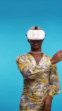 Siber uzayda nesnelere dokunan ve mavi arka planda sanal gerçekliği keşfeden şık elbiseli Afro-Amerikan transseksüel kişi ve VR gözlükleri.