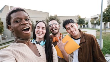 Black transgender person taking a selfie with a multiethnic group of friends while gesturing victory