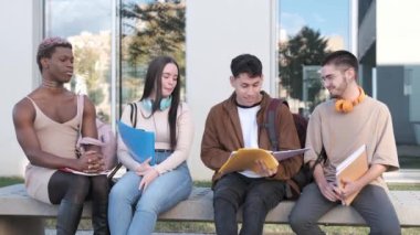 Video of a group of multiethnic friends and a transgender man sitting in line outside the university discussing class notes.