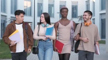 Slow motion video of a multiethnic group of students and a transgender person walking together while talking in the university