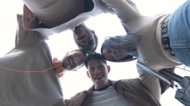 Slow motion video with low angle view of a group of students of different ethnicities hugging each other in a circle while looking down together