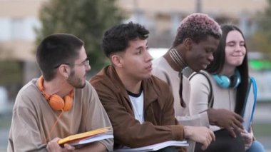 Slow motion video of a serious and relaxed multicultural group of students with a transgender person talking while sitting outdoors