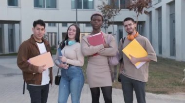 Çok ırklı mutlu bir öğrenci grubunun ve transseksüel bir Afrikalı 'nın üniversite kampüsünün önünde kameraya gülümseyişinin yavaş çekim videosu.
