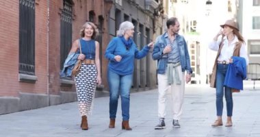 Bir grup olgun insanın cadde boyunca sohbet edişinin yavaş çekim videosu.