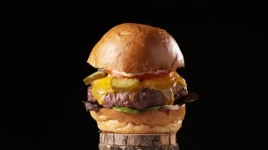 Peynirli, turşulu, domatesli, salatalı ve soslu nefis sulu sığır burger. Gerçek gibi görünüyor. Yavaş çekim 4k