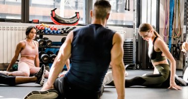 Spor salonundaki güçlü sporcular spor yaparken spor salonunda birlikte antrenman yapıyor ve bacaklarını esnetiyorlar.