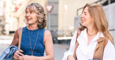 Üç şık olgun insan sokakta konuşuyor ve gülümsüyor.