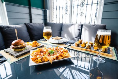 İştah açıcı yüksek oranda nacho ve hamburger çeşitli tabakların yanında servis edilir ve restoranda bira içilir.