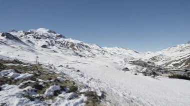 İspanya 'daki kayak merkezinde kayak yapan insanların kış günü yamaçtaki karlı dağların yakınında bulutsuz mavi gökyüzünün altında güneş ışığı altında görüntüsü. Portalet Formigal