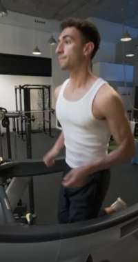 Spor salonunda koşu bandında terleyen bir adamın yavaş çekim videosu.