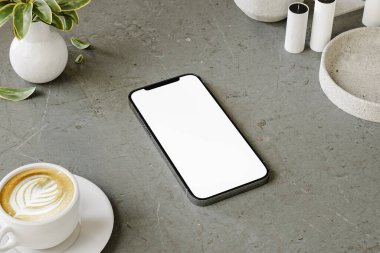 Bir sehpada bir fincan kahveyle bir cep telefonunun taklidini yap.