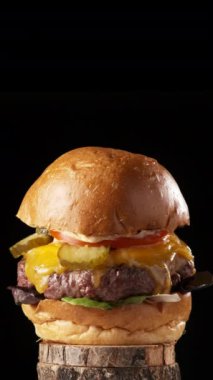 Peynirli, turşulu, domatesli, salatalı ve soslu nefis sulu sığır burger. Yavaş çekim dikey yönelimi