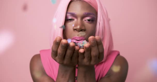 ビデオ トランスジェンダーのアフリカ人のスタジオで ピンクのドレスを吹くConetti — ストック動画