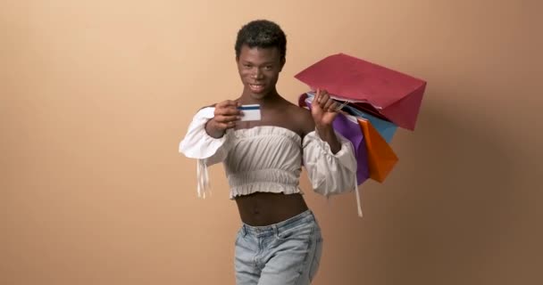 ショッピングバッグを持っているクレジットカードを示す幸せなトランスジェンダーの人物のスタジオでのビデオ — ストック動画