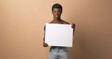 Elinde boş bir panelle gülümseyen Afrikalı bir transseksüelin video stüdyosunda.