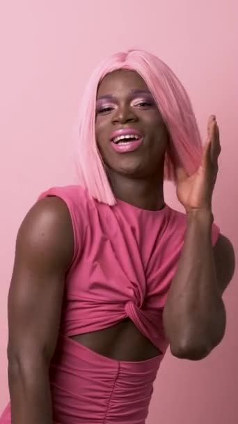 年轻快乐的非洲裔美国变装皇后 戴着化装假发 以女性的方式移动 同时在粉色背景下共同玩流行娃娃的真实时间 — 图库视频影像
