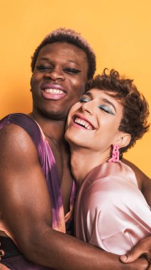 Makyajlı, moda elbiseli, sarılıp gülümseyen bir çift.