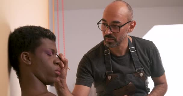 Artista Maquillaje Masculino Haciendo Maquillaje Una Persona Transgénero Africana Concepto — Vídeo de stock