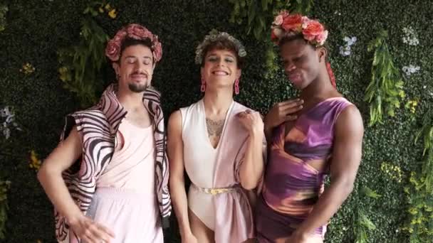 カラフルなドレスと花の冠でポーズする3人の多民族トランスジェンダーの人々のビデオ — ストック動画