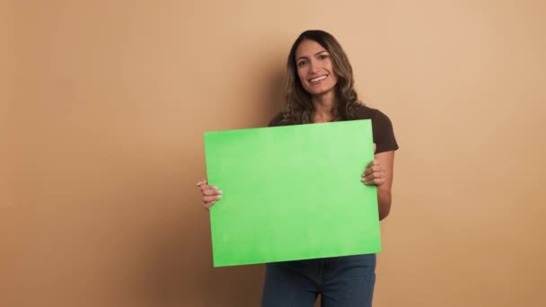 Wideo Beżowym Tłem Uśmiechniętej Kobiety Trzymającej Zielony Sztandar Chromowy Gestykulujący — Wideo stockowe