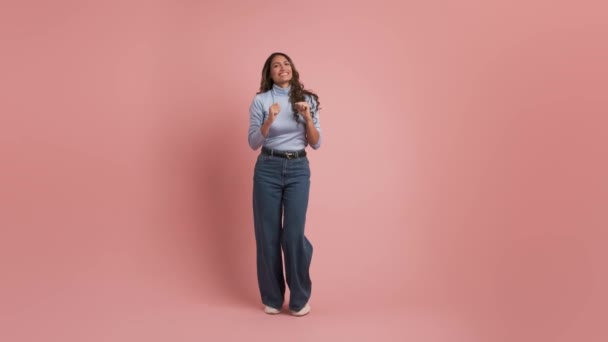 30多岁的成年科洛曼族妇女穿着休闲装 在素面朝天的浅粉色背景工作室里跳舞 — 图库视频影像