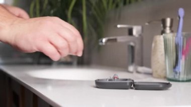 Yetişkin bir adamın banyodan işitme cihazını alışının yavaş çekim videosu.