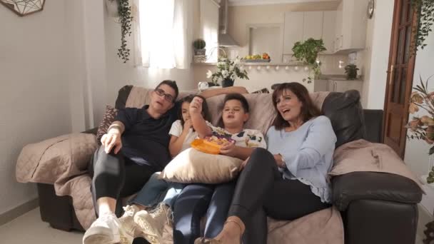 自宅でテレビを見ているソファーに一緒に座っている非規範的な家族のスローモーションビデオ — ストック動画