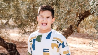 Genç bir çocuk tarlanın ortasında kameraya gülümsüyor.