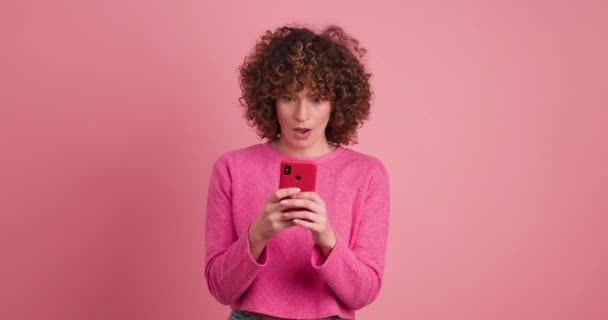 Ενθουσιασμένη Νεαρή Γυναίκα Ροζ Casual Ρούχα Σγουρά Μαλλιά Έλεγχο Smartphone — Αρχείο Βίντεο