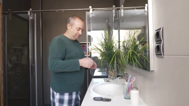 トイレの耳に補聴器を置く大人の男性のプロフィールのビデオ — ストック動画