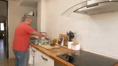 Evde bulaşıkları yıkarken yetişkin bir adama yaklaşan video.