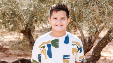 Genç bir çocuk tarlanın ortasında kameraya gülümsüyor.