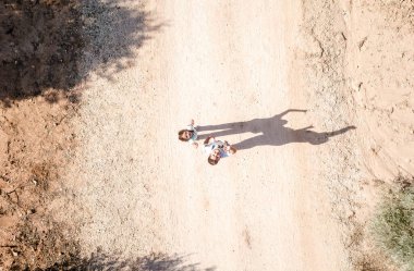 Güneşli bir günde zeytin ağaçlarının arasında koşan iki çocuk.