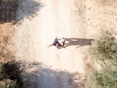 Ebeveynler güneşli bir günde zeytin ağaçlarının arasında dönüyorlar.