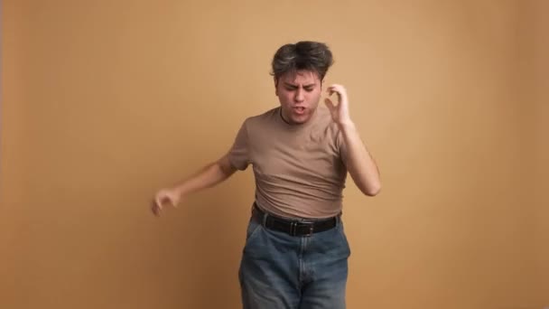 Випадковий Молодий Чоловік Стрибає Танцює Святкування Студії Коричневим Фоном — стокове відео